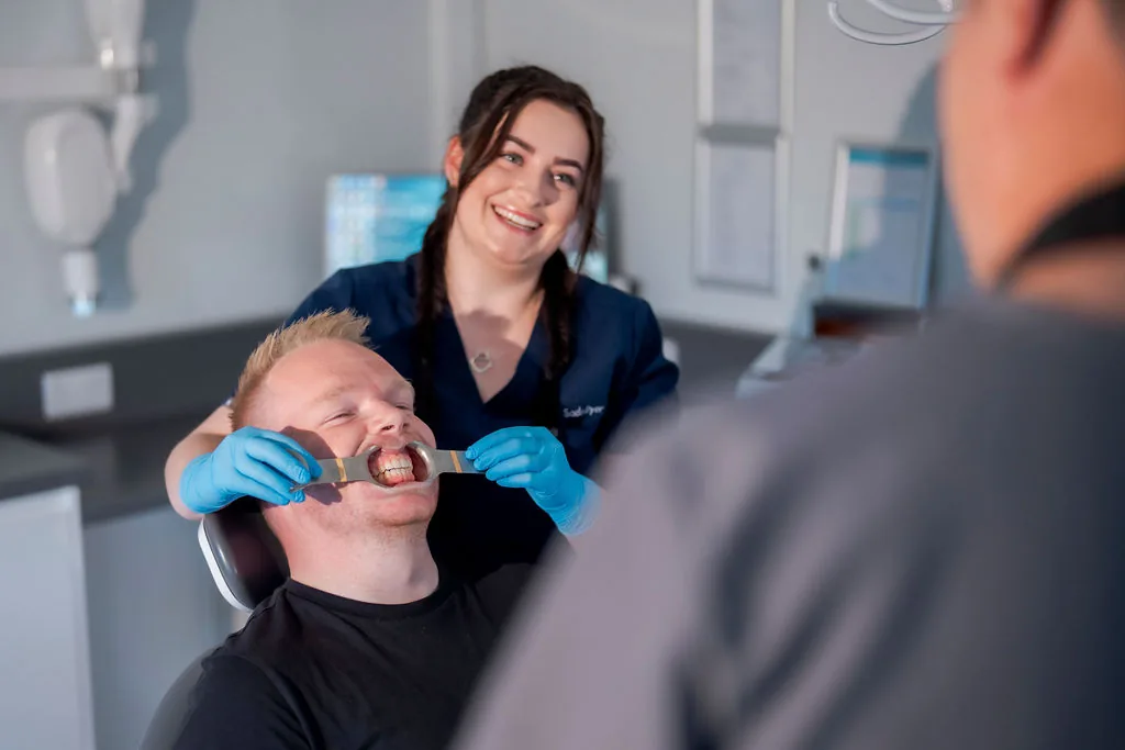 A patient receiving care with the dental team in a treatment room.